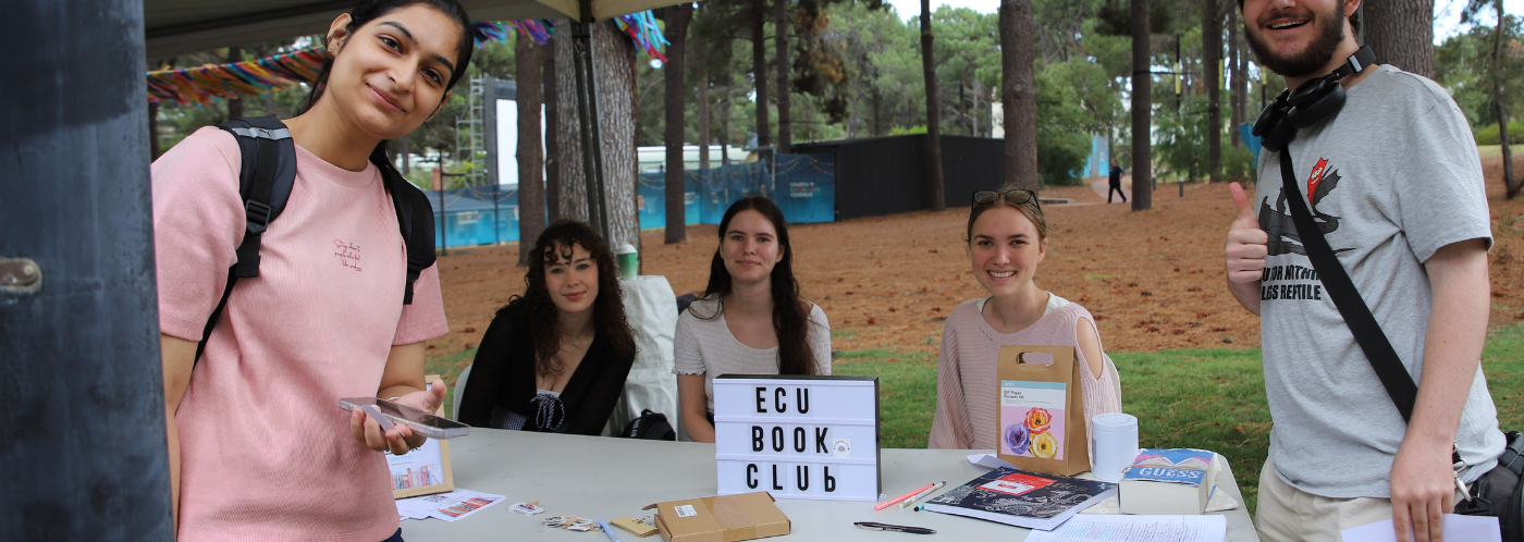 Committe members from ECU Book Club at their stall at Guild Fair 2025 smiling at the camera